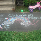 children's chalk drawing on a sidewalk of a rainbow and "Columbus House" written out