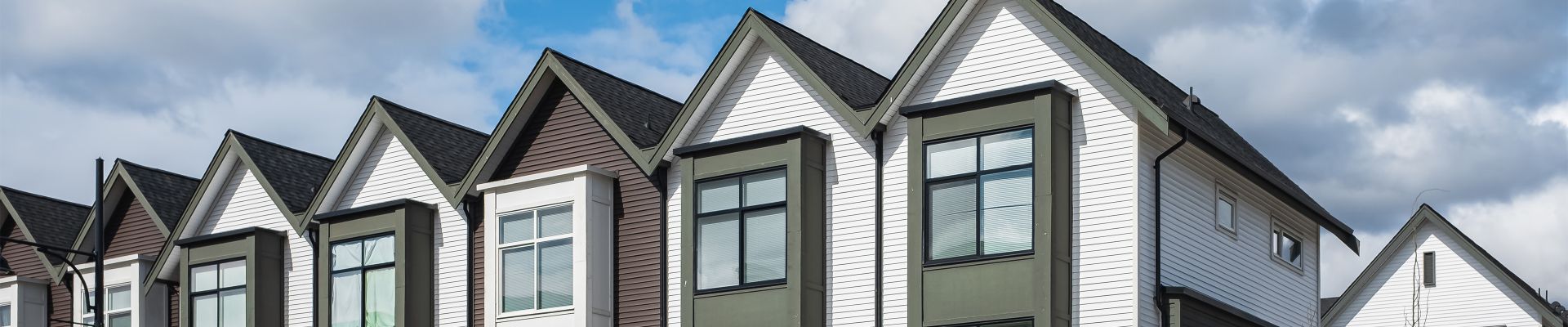 The tops of a row of white and burgundy condos with modern-style windows.