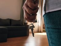 Close up of a person holding a key to a new place while standing inside the living room