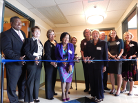 Group of people posing together and cutting the ribbon at an opening ceremony.