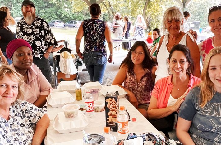 Group of women posing together at a table at an outdoor event. 