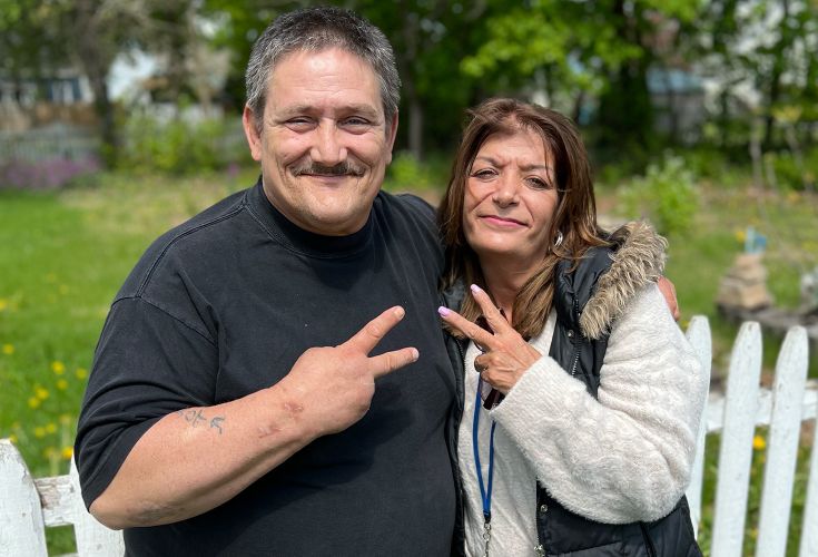 Man and woman posing together with peace signs outside