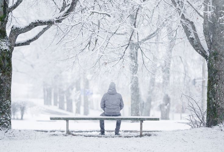 Man sitting on a bench alone in the snow