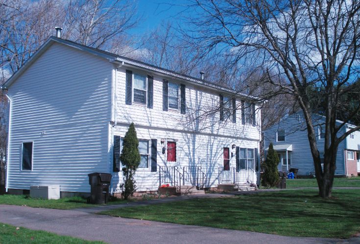 White two-family house with red doors and black shutters.