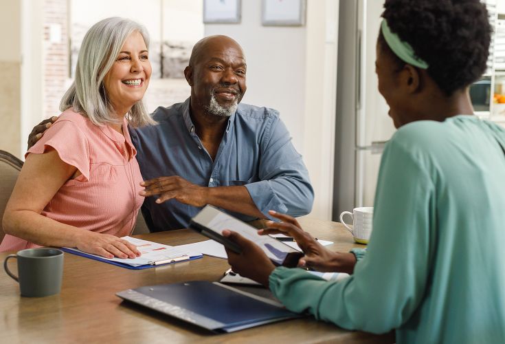 Husband and wife smiling and listening to an advisor speaking