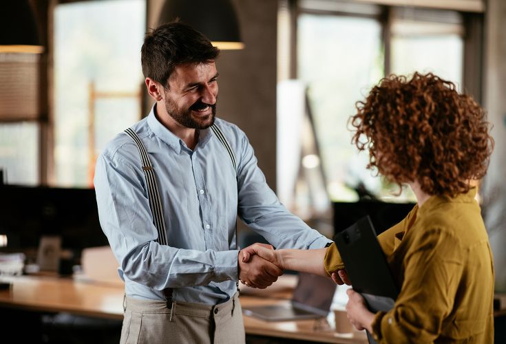 Man shaking woman's hand inside of an office space