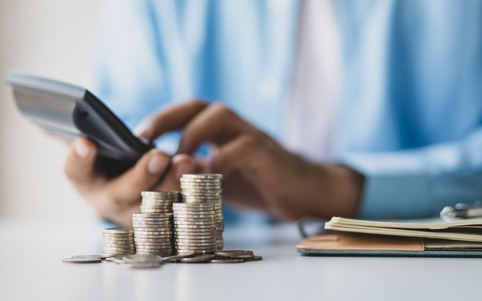 Person using their phone with a stack of coins in focus
