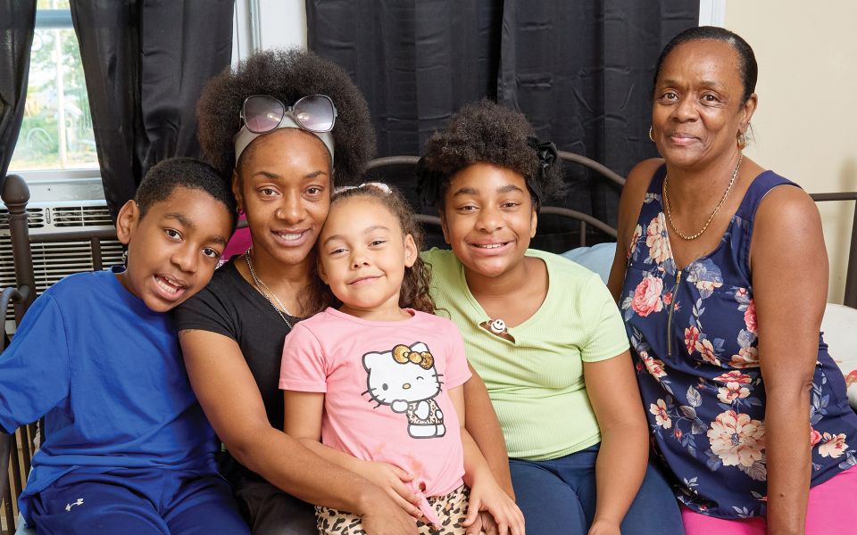 Family posing close together while sitting on a bed