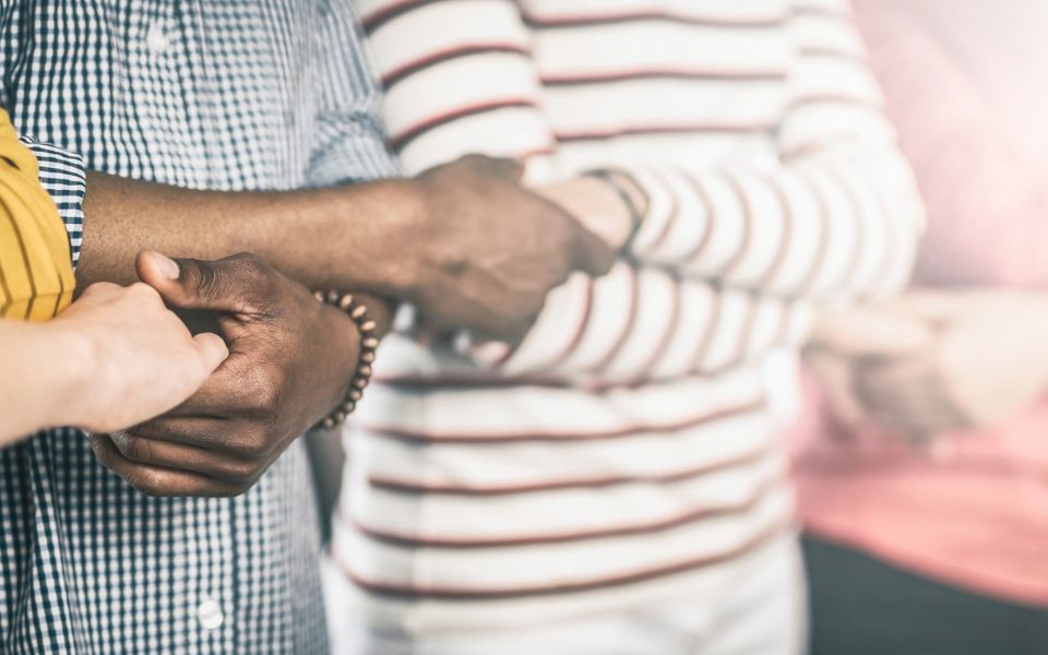 people standing next to each other linking hands
